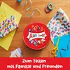 A flat lay of gift-wrapping supplies and a round tin of chocolates, with text overlay at the bottom. Produktbild-Vorschau