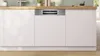A built-in dishwasher integrated into a modern kitchen counter with white cabinets. Produktbild-Vorschau