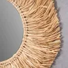 A close-up view of a round mirror with a woven seagrass frame. Produktbild-Vorschau