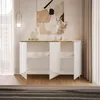 A white high-gloss sideboard with gold accents and legs, featuring open doors and shelves, displayed in a well-lit room with a painting on the wall and sheer curtains. Produktbild-Vorschau