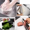 A collage of four images showing different uses of a stainless steel cutting board: kneading dough, rolling dough, chopping lettuce, and slicing ham. Produktbild-Vorschau