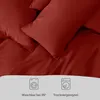 Close-up of dark red bedding with laundry care symbols and text at the bottom. Voir les images du produit