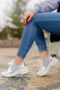 A person is sitting outdoors, showing off their shoes. Produktbild-Vorschau