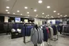 Interior of a men's clothing store with suits and jackets displayed on racks. Produktbild-Vorschau