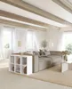 A modern living room with a large sectional sofa, a white cube shelving unit, and a coffee table. The room has large windows with white curtains and exposed wooden ceiling beams. Produktbild-Vorschau