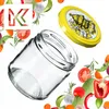 A glass jar and its lid are shown surrounded by various vegetables and herbs. Podgląd zdjęcia produktu