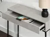 A close-up shot of a console table with an open drawer, revealing a magazine inside. A black lamp is visible on the table's surface. Náhled obrázku produktu