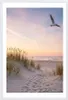 A framed picture of a beach scene at sunset with a seagull flying. Produktbild-Vorschau