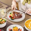 A person is eating a meal with a steak, vegetables, salad, and soup, using a MALACASA dinnerware set. Náhled obrázku produktu