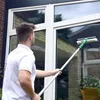 A man is cleaning a large window with a long-handled squeegee. Produktbild-Vorschau
