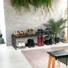 A shoe rack with various shoes on display in front of a concrete wall with hanging plants. Podgląd zdjęcia produktu