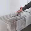 A person's hands are shown hanging towels on a wall-mounted drying rack. Produktbild-Vorschau