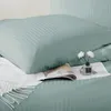 A close-up view of a pillow and bedding with a magazine and a small diffuser with flowers. Podgląd zdjęcia produktu