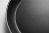 A close-up view of the textured surface and rim of a black frying pan. Náhled obrázku produktu