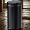 A black sensor trash can is placed on a wooden floor in front of a wooden door. Náhled obrázku produktu