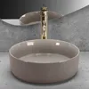 A beige ceramic vessel sink with a gold faucet in a bathroom setting. Náhľad obrázku produktu