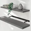 Two gray shelves mounted on a white wall. The top shelf has books, a plant, and a vase. The bottom shelf has a black bracket. Produktbild-Vorschau