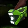 A hand holding a green and gray multi-functional device, possibly outdoors at night. Produktbild-Vorschau
