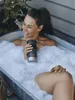 A woman is relaxing in a bubble bath outdoors, holding a Contigo travel mug. Náhľad obrázku produktu