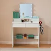 A white vanity table with a lighted mirror, makeup, and a hairdryer holder. Produktbild-Vorschau