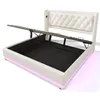 A white upholstered bed frame with a tufted headboard and LED strip lighting around the base is shown with the mattress support lifted to reveal storage space beneath. The lighting is a soft pink hue. Voir les images du produit