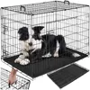 A black wire dog crate with a black and white border collie dog inside. A hand is shown reaching into the crate from the bottom left. Produktbild-Vorschau