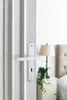 A white door handle is shown in the foreground, with a bedroom scene blurred in the background. Produktbild-Vorschau
