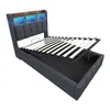 A modern upholstered bed frame with its mattress support system lifted to reveal storage space underneath. The headboard features integrated LED lighting. Náhled obrázku produktu