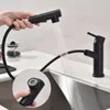 A person is using a black kitchen faucet with a pull-out spray head over a stainless steel sink. Produktbild-Vorschau