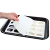A hand is holding a white scraper over a baking tray with a mold for small baked goods. Produktbild-Vorschau