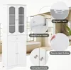 A white cabinet with glass doors and a drawer, shown in a bathroom setting with a bathtub in the background. Insets highlight features like magnetic catches, metal drawer slides, easy-to-clean surfaces, and convenient knobs. Podgląd zdjęcia produktu
