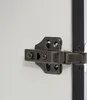 A close-up view of a cabinet hinge attached to a white surface and a black frame. Anteprima dell’immagine prodotto