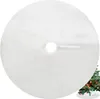A white, fluffy Christmas tree skirt with a hole in the center for the tree trunk. A small portion of a decorated Christmas tree is visible in the bottom right corner. Náhľad obrázku produktu