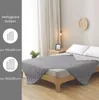 A bed with a gray quilted blanket, with informational text and icons on the left side. Náhled obrázku produktu