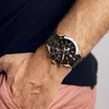 A man's arm wearing a black and gold watch. Voir les images du produit