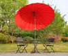 A red patio umbrella with a table and two chairs set up on a paved area in a garden. Anteprima dell’immagine prodotto