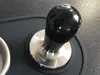 A close-up shot of a coffee tamper on a dark mat. Produktbild-Vorschau
