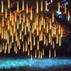 Fairy lights hanging from a tree branch, illuminating a garden at night. Produktbild-Vorschau