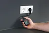 A hand holds a voltage tester plugged into a wall socket. Náhľad obrázku produktu
