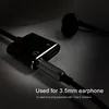 A close-up shot of a black USB-C to 3.5mm audio adapter with a headphone jack and a charging port, connected to a pair of black earbuds. Produktbild-Vorschau