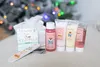 A Christmas-themed gift set with toiletries and a nail file, placed on a soft surface with a blurred Christmas tree in the background. Produktbild-Vorschau