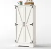 A white cabinet with two doors and decorative metal accents, set against a plain white background. Decorative items are placed on top of the cabinet. Podgląd zdjęcia produktu