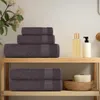Towels neatly stacked on a wooden shelf in a bathroom setting. Podgląd zdjęcia produktu