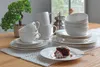 A set of white ceramic dessert plates and cups are arranged on a wooden table with a white lace placemat. Produktbild-Vorschau