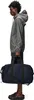 A person is shown from the side, holding a duffel bag. Produktbild-Vorschau
