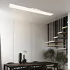 A modern dining room with a sleek ceiling light, a wooden table with chairs, and a staircase. Anteprima dell’immagine prodotto