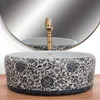 A close-up shot of a decorative basin with a golden faucet, set against a blurred mirror reflection. Anteprima dell’immagine prodotto
