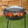 A cast iron grill pan is placed on a barbecue grill over glowing coals, set on a grassy lawn with a wooden fence in the background. Náhľad obrázku produktu
