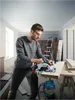 A man is using a Bosch circular saw to cut a piece of wood in a room under renovation. Anteprima dell’immagine prodotto