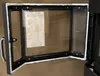 A fireplace door with glass and a handle, lying flat against a brown surface. Náhled obrázku produktu